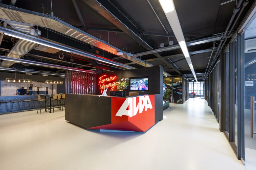 Moderne ontvangstbalie van het bedrijf AWA aan de Anthony Fokkerweg met neontekst "Forever Young" en industriële inrichting.